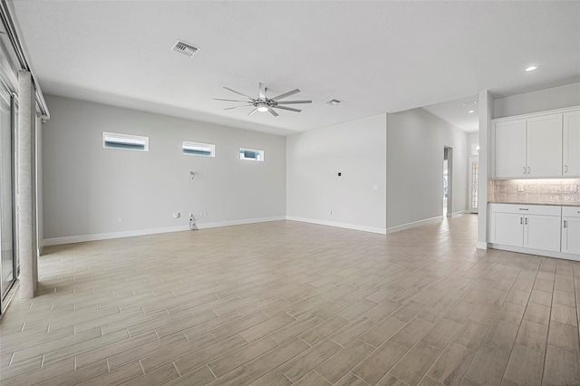 unfurnished living room with light wood finished floors, visible vents, baseboards, and ceiling fan