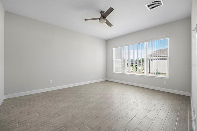 spare room with visible vents, baseboards, wood finished floors, and a ceiling fan