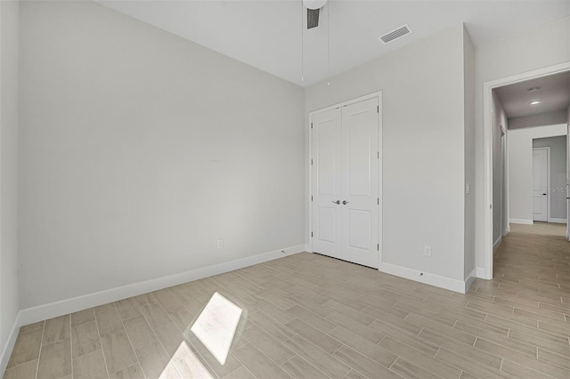 unfurnished bedroom with light wood-type flooring, visible vents, a closet, baseboards, and ceiling fan