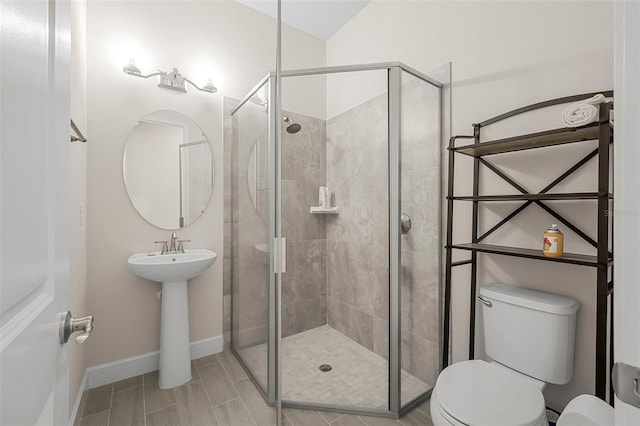 bathroom featuring a stall shower, toilet, and baseboards