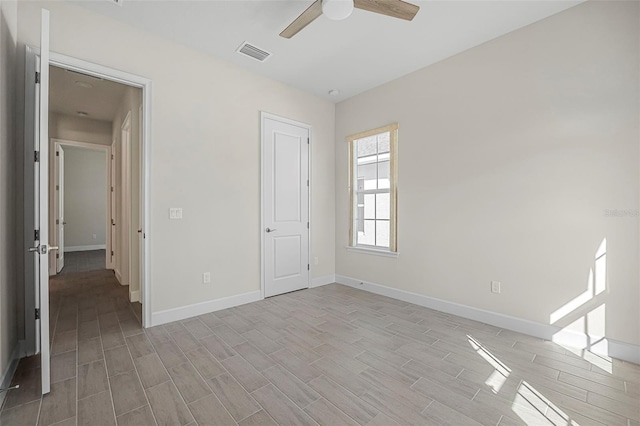 unfurnished room with visible vents, baseboards, wood finish floors, and a ceiling fan