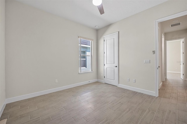 spare room featuring ceiling fan, visible vents, baseboards, and light wood-style flooring