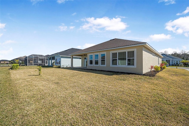 rear view of property featuring stucco siding and a yard