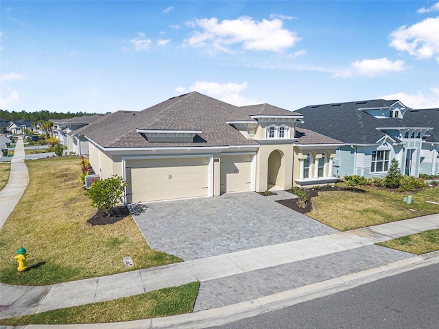 view of front of home with a front yard, decorative driveway, an attached garage, and stucco siding