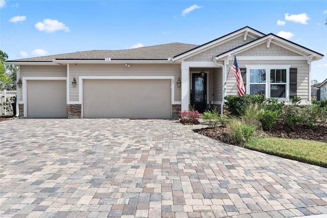 view of front of property featuring a garage, stone siding, and decorative driveway