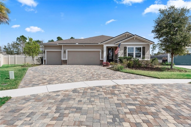 view of front of home with a garage, decorative driveway, fence, and stone siding