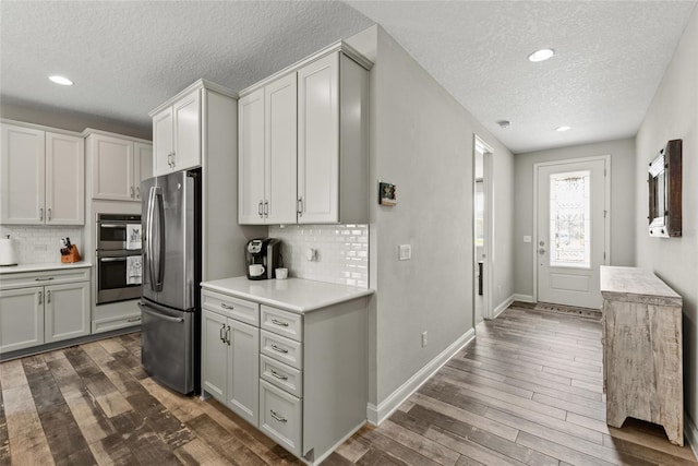 kitchen featuring freestanding refrigerator, dark wood-style flooring, light countertops, and baseboards