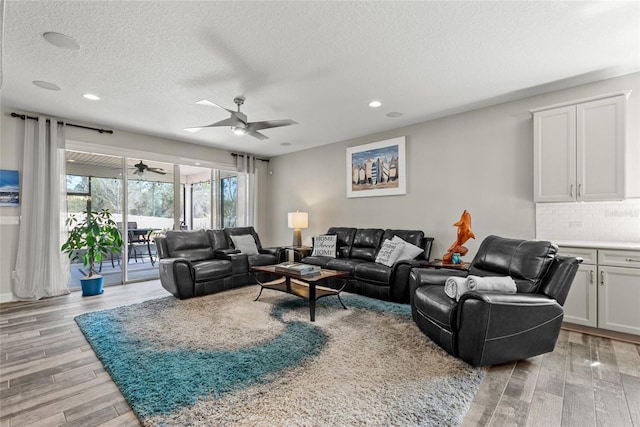 living area featuring light wood-type flooring, ceiling fan, a textured ceiling, and recessed lighting