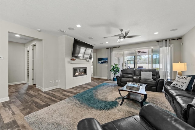 living room featuring a textured ceiling, a fireplace, baseboards, and wood finished floors