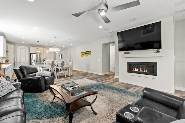 living area with a large fireplace, baseboards, ceiling fan, light wood-style floors, and recessed lighting