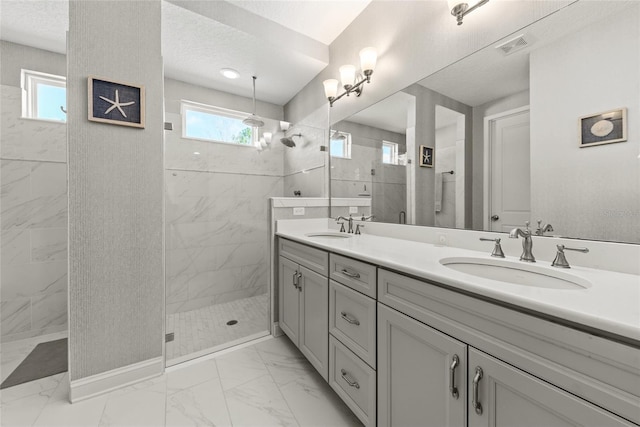 bathroom with a walk in shower, marble finish floor, and a sink