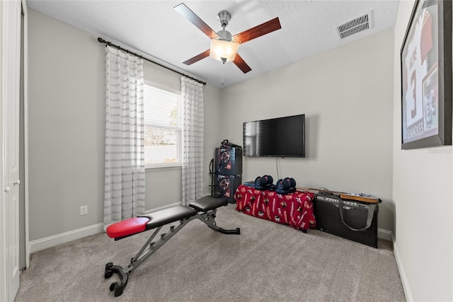 exercise room featuring baseboards, visible vents, ceiling fan, a textured ceiling, and carpet floors