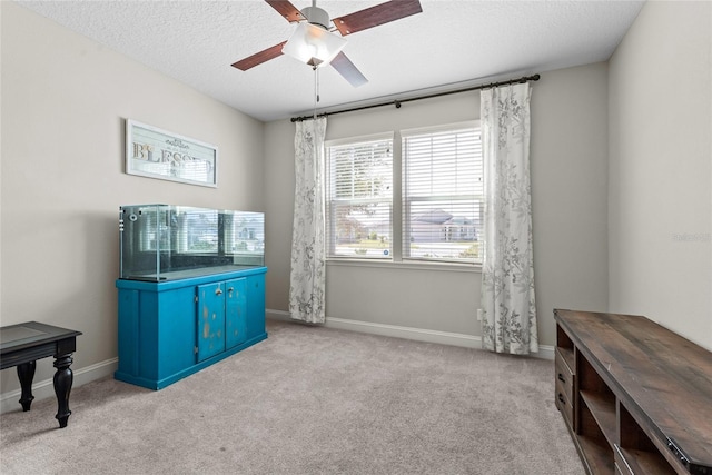 interior space with a ceiling fan, a textured ceiling, and baseboards