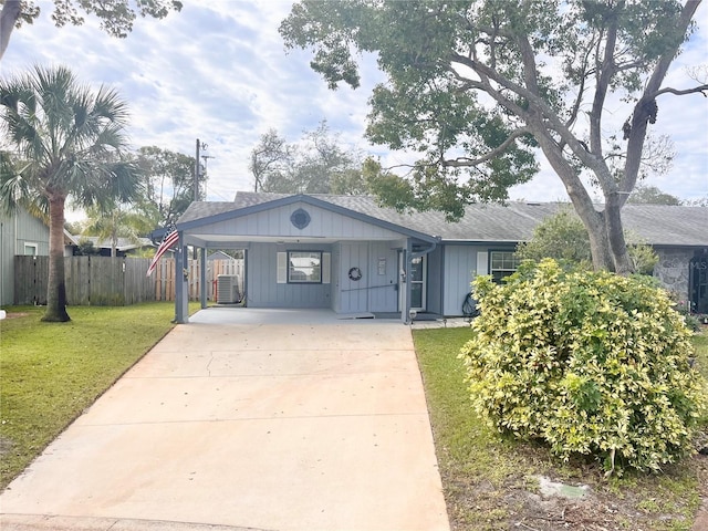 view of front facade featuring fence, concrete driveway, roof with shingles, a carport, and a front lawn