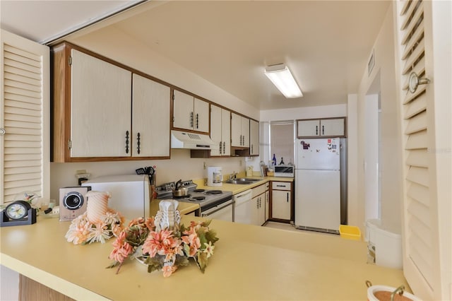 kitchen with light countertops, white appliances, a sink, and under cabinet range hood