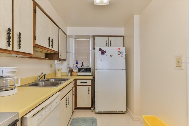 kitchen with white appliances, baseboards, light countertops, and a sink