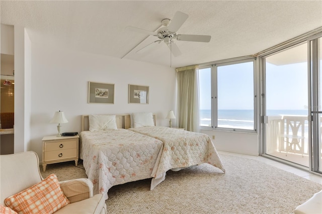 bedroom featuring a textured ceiling, a water view, a ceiling fan, and access to exterior