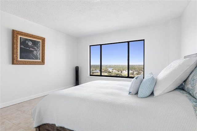 bedroom featuring a textured ceiling, light tile patterned floors, and baseboards