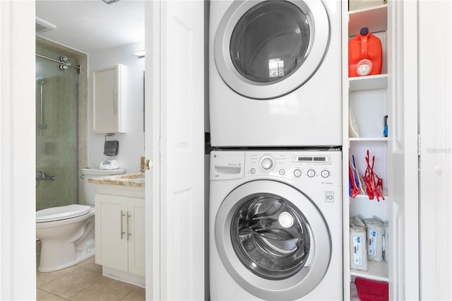 laundry room featuring stacked washer and clothes dryer, light tile patterned floors, visible vents, and laundry area