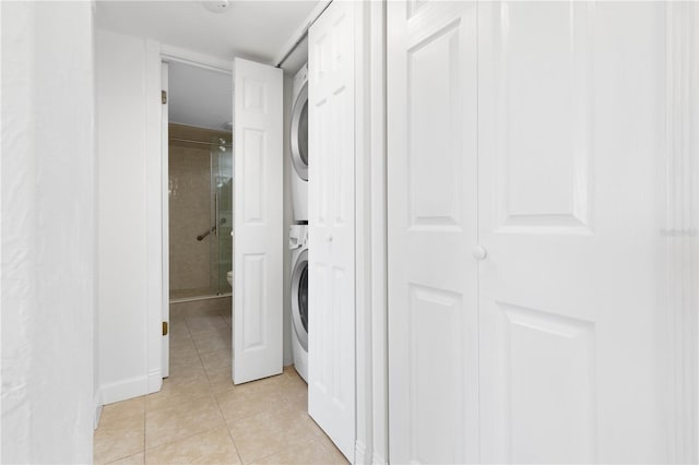 clothes washing area featuring stacked washer and dryer and light tile patterned flooring