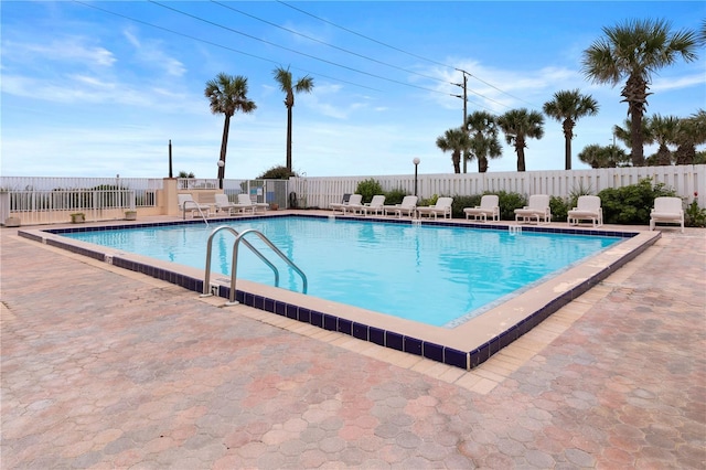 pool with a patio area and fence