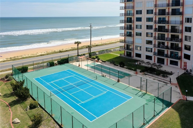 view of sport court featuring a water view, fence, and a beach view