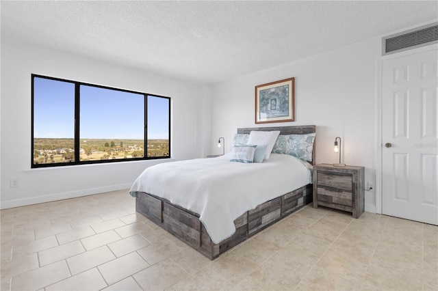 bedroom featuring visible vents, a textured ceiling, baseboards, and light tile patterned flooring