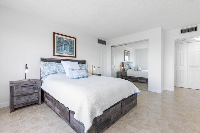 bedroom featuring a closet, visible vents, a textured ceiling, and baseboards