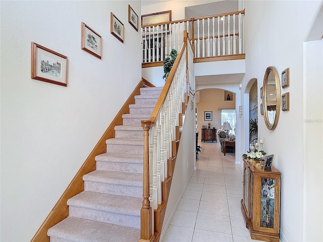 9 Cedar Hollow Ct, Palm Coast, FL 32137 - stairs with tile patterned flooring, a towering ceiling, arched walkways, and baseboards
