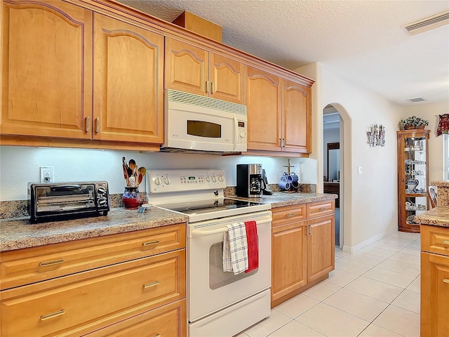 9 Cedar Hollow Ct, Palm Coast, FL 32137 - kitchen featuring a textured ceiling, light tile patterned floors, white appliances, visible vents, and arched walkways