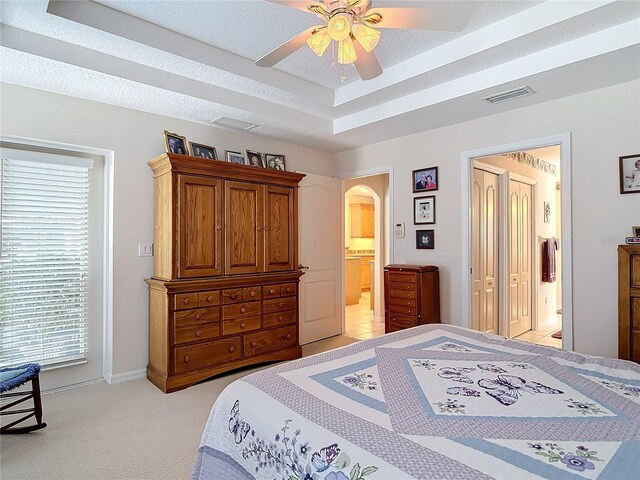 9 Cedar Hollow Ct, Palm Coast, FL 32137 - bedroom featuring light colored carpet, a raised ceiling, arched walkways, ensuite bath, and visible vents
