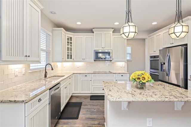 kitchen featuring pendant lighting, a sink, white cabinetry, appliances with stainless steel finishes, and light stone countertops