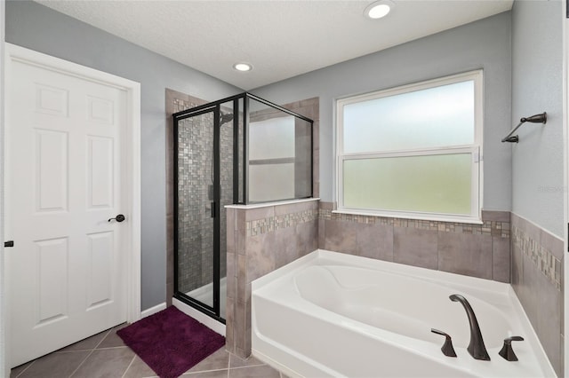 full bathroom with tile patterned floors, a bath, a shower stall, and a textured ceiling