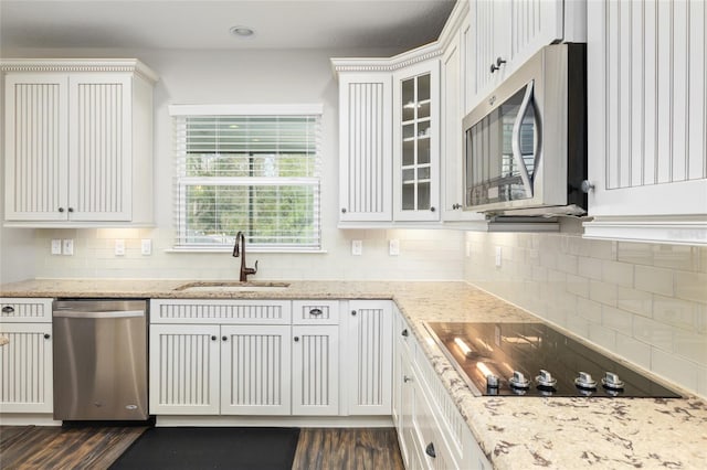 kitchen featuring tasteful backsplash, a sink, glass insert cabinets, stainless steel appliances, and dark wood-style flooring