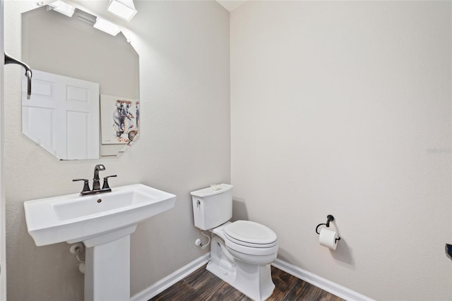 bathroom with a sink, toilet, baseboards, and wood finished floors