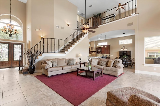 living area featuring light tile patterned floors, ceiling fan with notable chandelier, stairway, and baseboards
