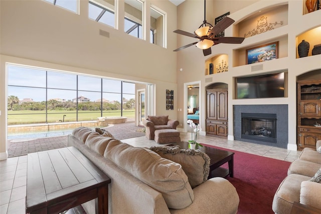 tiled living room featuring visible vents, a tiled fireplace, built in features, and a ceiling fan