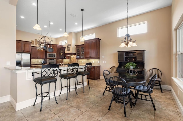 dining room featuring a chandelier, baseboards, recessed lighting, a high ceiling, and light tile patterned floors