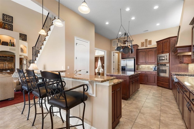 kitchen with an island with sink, light stone countertops, a breakfast bar, stainless steel appliances, and visible vents