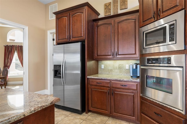 kitchen featuring backsplash, light tile patterned flooring, light stone counters, visible vents, and appliances with stainless steel finishes
