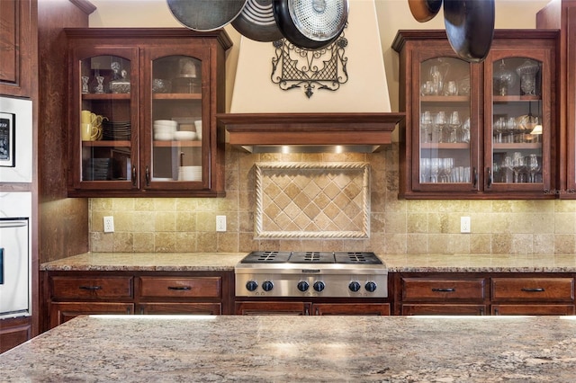 kitchen with glass insert cabinets, stainless steel gas cooktop, wall oven, and tasteful backsplash