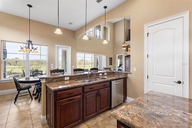 kitchen with stainless steel dishwasher, pendant lighting, a sink, and dark stone counters