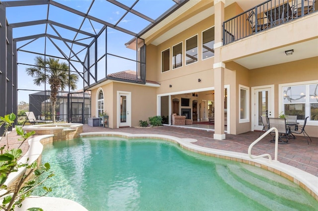view of pool with a pool with connected hot tub, glass enclosure, and a patio area