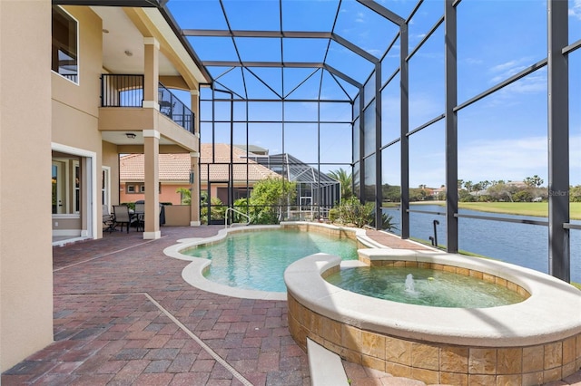 view of swimming pool with a patio, a water view, a pool with connected hot tub, and glass enclosure