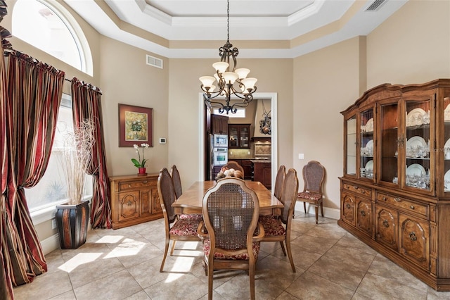 dining space with baseboards, a tray ceiling, visible vents, and a notable chandelier