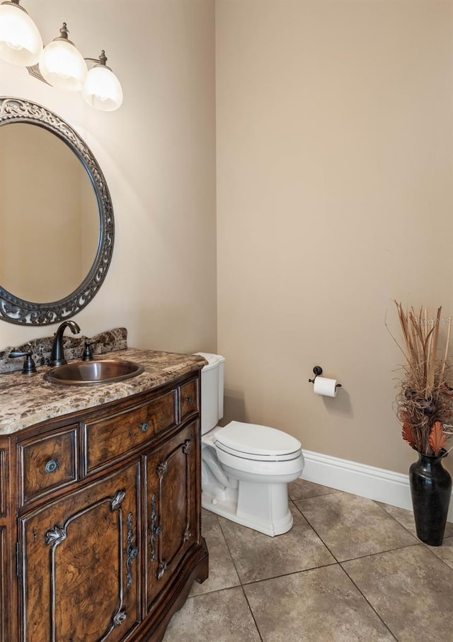 half bathroom with toilet, vanity, tile patterned floors, and baseboards