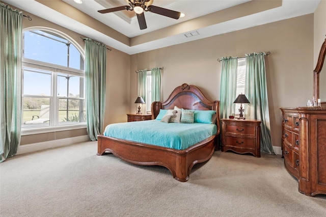 bedroom featuring a ceiling fan, a tray ceiling, carpet, and baseboards