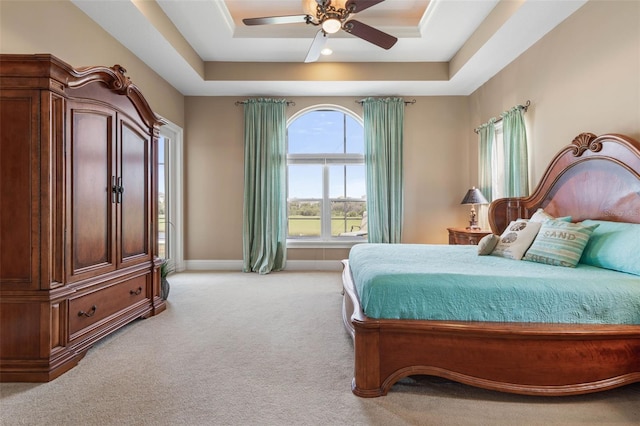 bedroom with a tray ceiling, light colored carpet, ceiling fan, and baseboards