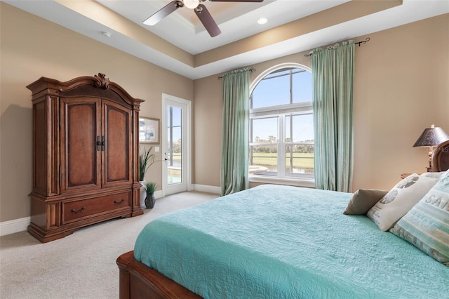 bedroom with light colored carpet, access to outside, baseboards, a raised ceiling, and ceiling fan