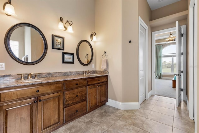 full bath featuring double vanity, tile patterned flooring, a sink, and baseboards
